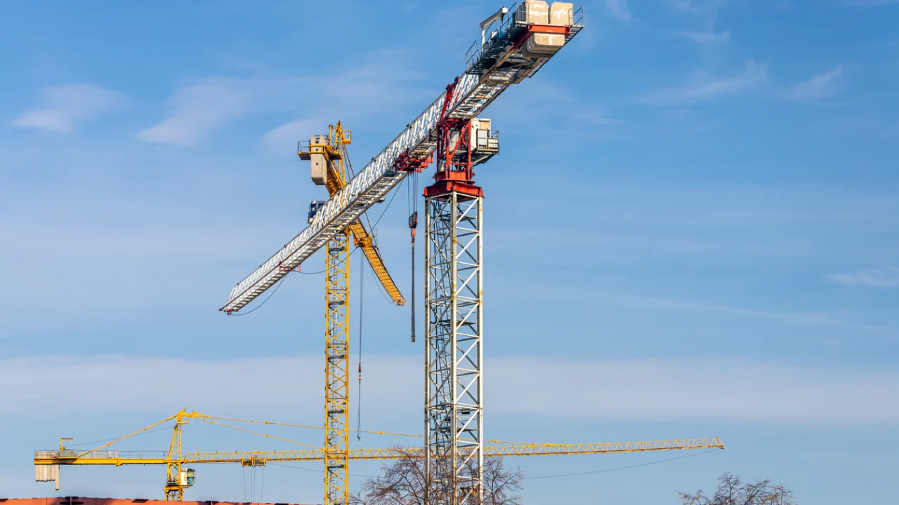 Grua de construção civil sobre céu azul claro em canteiro de obras