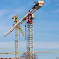 Grua de construção civil sobre céu azul claro em canteiro de obras