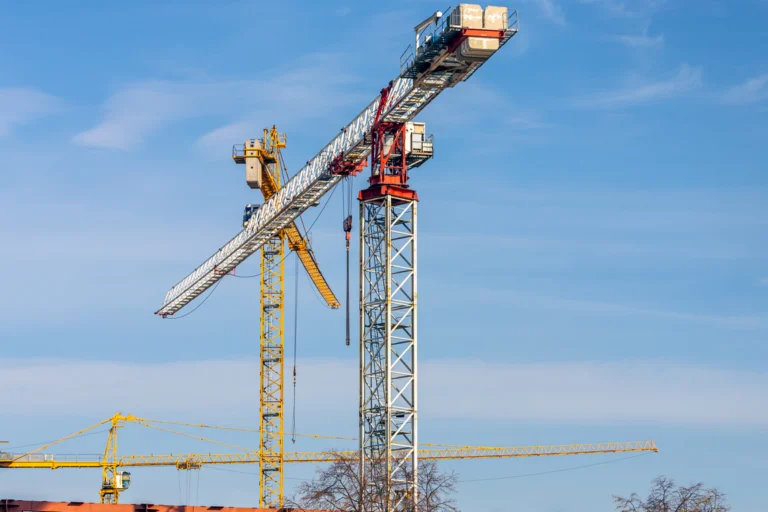 Grua de construção civil sobre céu azul claro em canteiro de obras