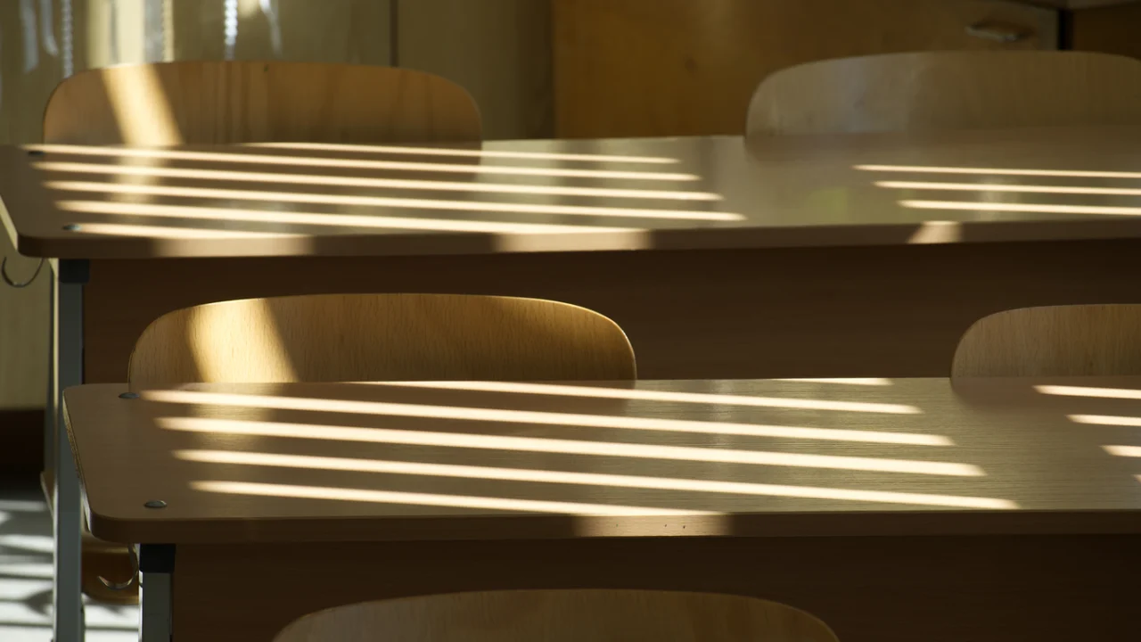 Carteiras de escola pública iluminadas pela luz da manhã que entra pela janela