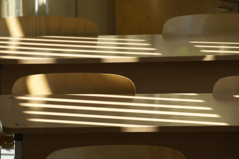 Carteiras de escola pública iluminadas pela luz da manhã que entra pela janela
