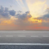 Rodovia estadual de pista simples ao amanhecer, com asfalto e acostamento e vegetação às margens