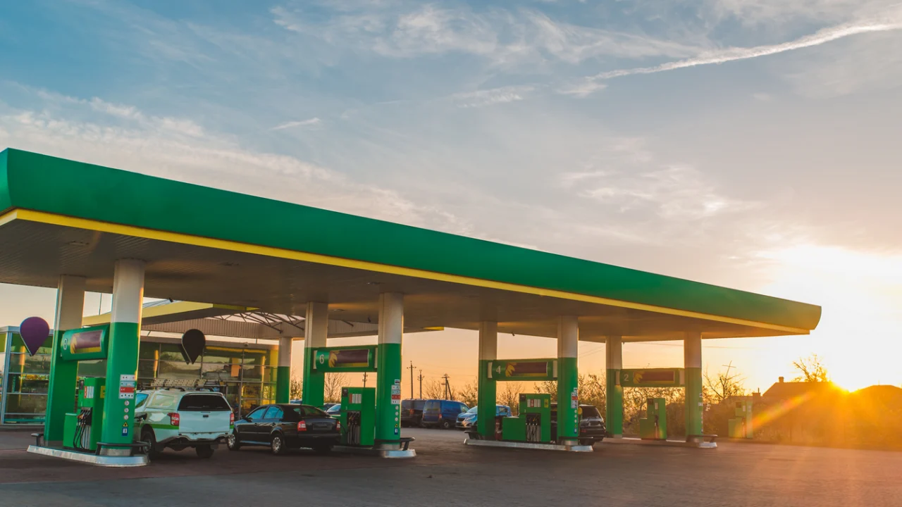 Posto de gasolina de bairro em Atibaia ao amanhecer, com bombas de combustível alinhadas e pista molhada pela chuva fina