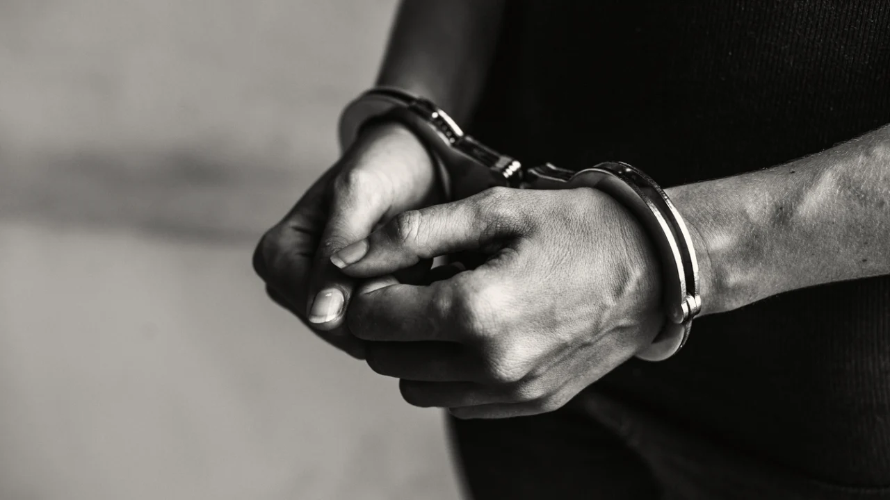 Mãos algemadas de homem detido, em registro fotográfico em preto e branco