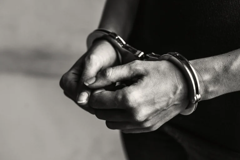Mãos algemadas de homem detido, em registro fotográfico em preto e branco