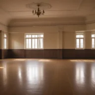Salão amplo de piso de madeira iluminado pela luz da manhã, com janelas altas e paredes claras
