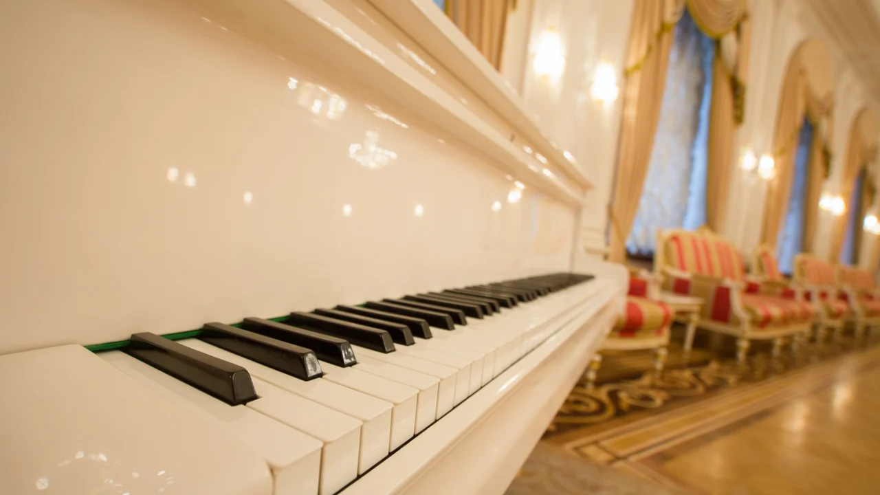 Teclado de um piano branco em um salão, em fotografia de banco.