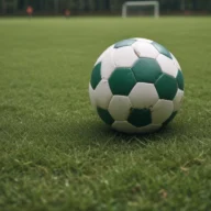 Bola de futebol sobre o gramado de um campo ao anoitecer, com a trave ao fundo