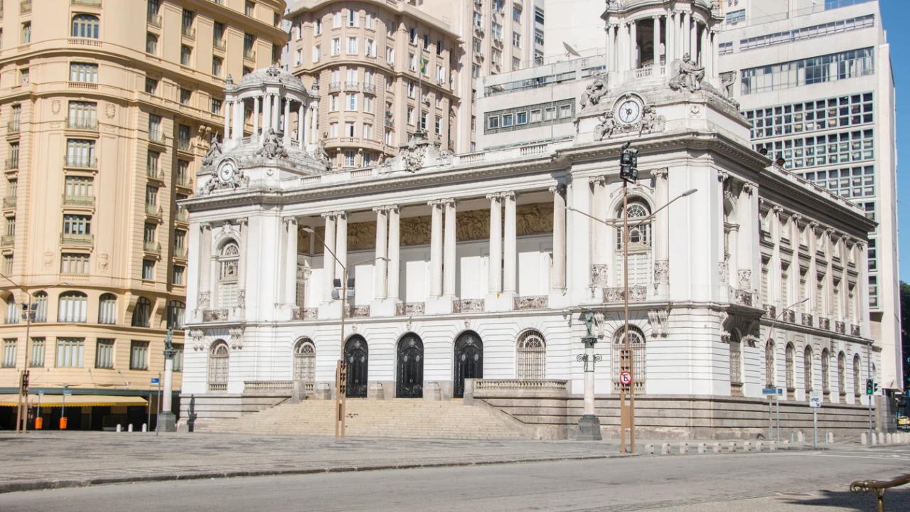 Fachada de prédio público com colunas e escadaria, vista da calçada em dia de sol