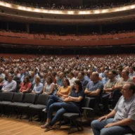 Auditório para encontro sobre gestão municipal, com cadeiras, microfones e pastas, sem pessoas.