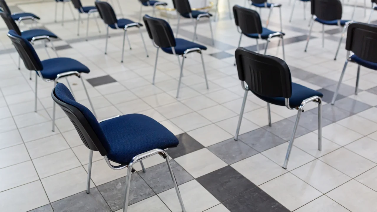 Cadeiras enfileiradas em um salão comunitário antes do atendimento ao público