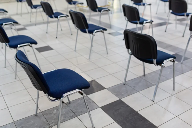 Cadeiras enfileiradas em um salão comunitário antes do atendimento ao público