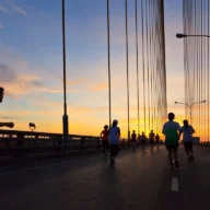 Corredores em pelotão em uma avenida arborizada durante uma corrida de rua pela manhã