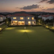 Bairro residencial com casas ao anoitecer, luzes acesas e céu alaranjado