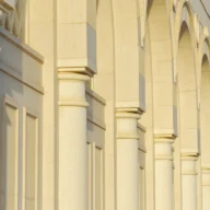 Fachada de prédio público com colunas de pedra iluminadas pelo sol da manhã