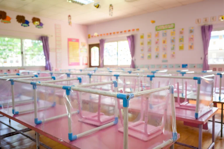 Sala de creche municipal com berços, mesinhas coloridas e cartazes infantis nas paredes