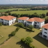 Vista aérea de bairro residencial com casas de telhado vermelho e área verde ao redor, em uma cidade do interior
