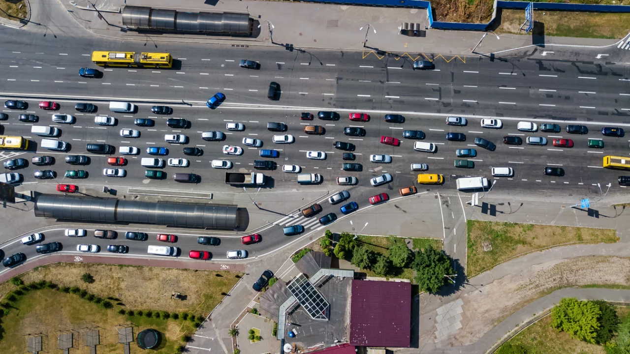 Vista aérea de rodovia com trânsito intenso e fila de carros em trecho com obra no asfalto, ao amanhecer