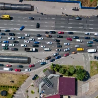 Vista aérea de rodovia com trânsito intenso e fila de carros em trecho com obra no asfalto, ao amanhecer