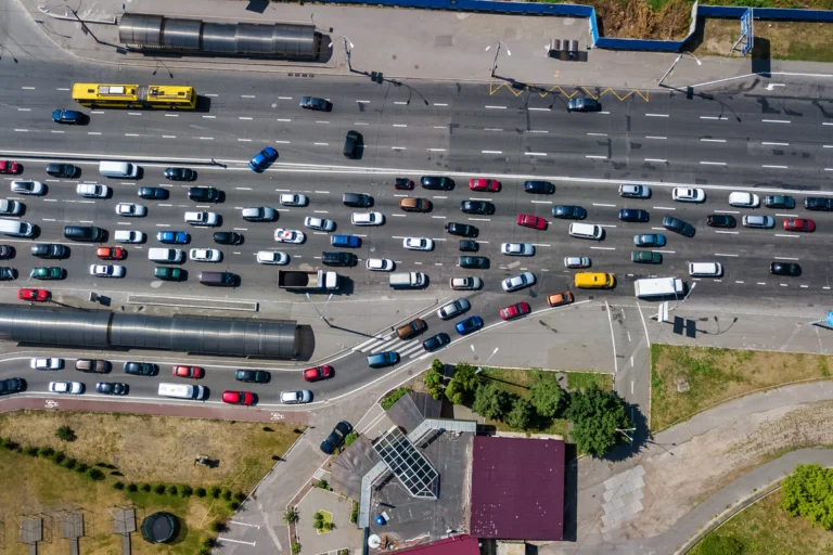 Vista aérea de rodovia com trânsito intenso e fila de carros em trecho com obra no asfalto, ao amanhecer