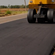 Máquina e rolo compactador em obra de recapeamento de estrada rural