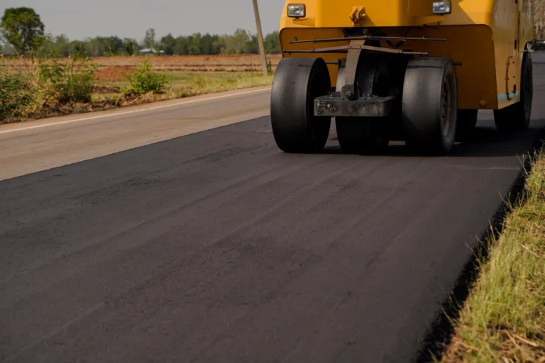 Máquina e rolo compactador em obra de recapeamento de estrada rural