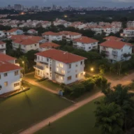 Vista ampla de prédios residenciais baixos, ruas e árvores ao entardecer.