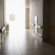 Corredor claro de unidade hospitalar, com corrimãos e piso de cerâmica