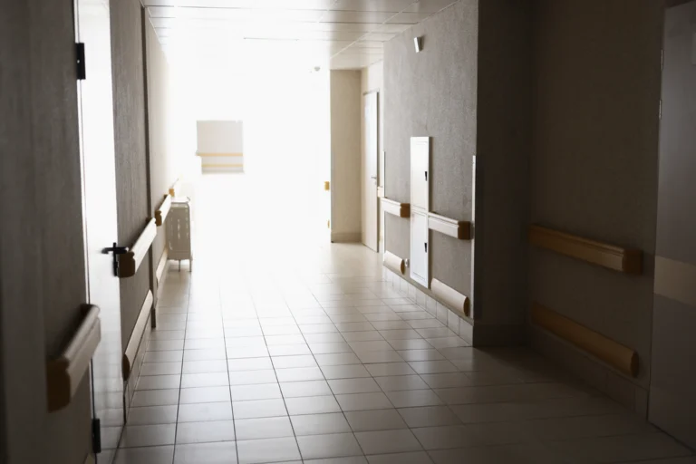Corredor claro de unidade hospitalar, com corrimãos e piso de cerâmica