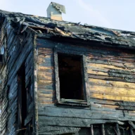 Estrutura de madeira de uma casa destruída pelo fogo, vista da rua ao amanhecer