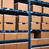 Caixas de papelão organizadas em prateleiras metálicas de um armazém.