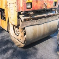 Rolo compactador em operação sobre asfalto em obra de recuperação de pavimento em rodovia