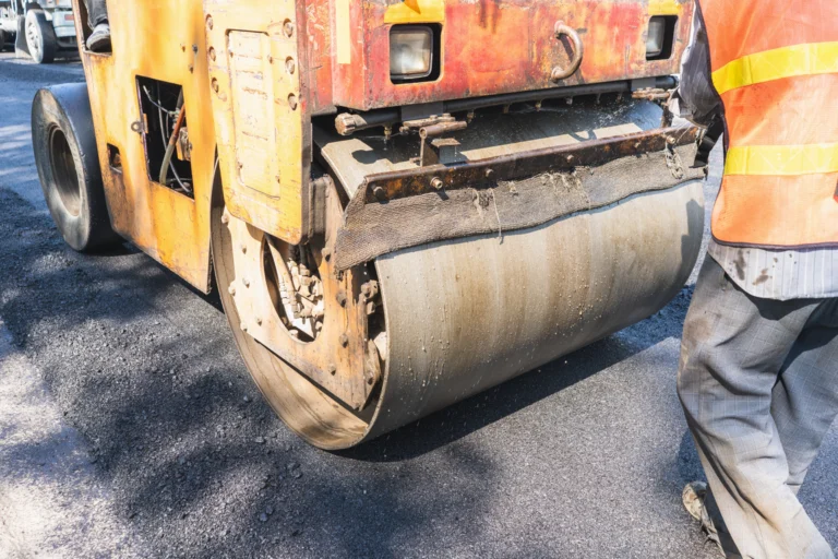 Rolo compactador em operação sobre asfalto em obra de recuperação de pavimento em rodovia