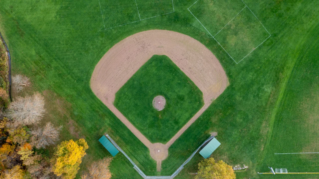 Vista aérea de campo de beisebol com diamante de terra batida cercado por gramado verde