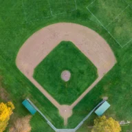 Vista aérea de campo de beisebol com diamante de terra batida cercado por gramado verde