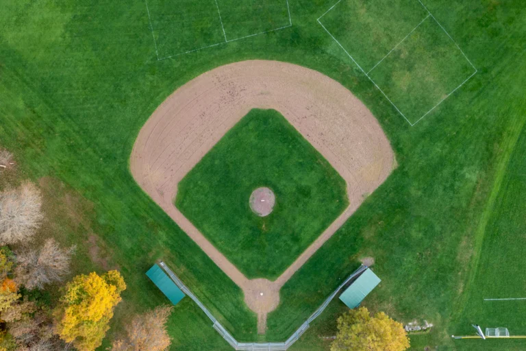 Vista aérea de campo de beisebol com diamante de terra batida cercado por gramado verde