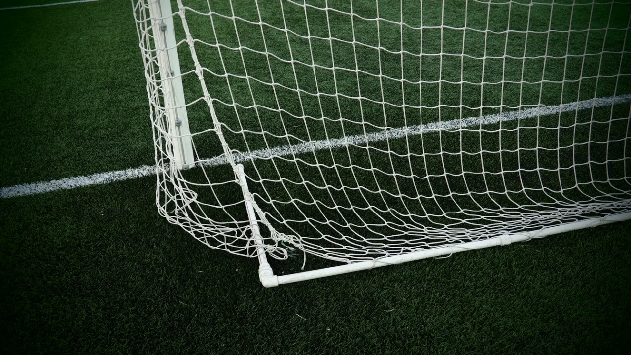 Rede de gol de campo de futebol com gramado aparado e linha branca demarcando a área