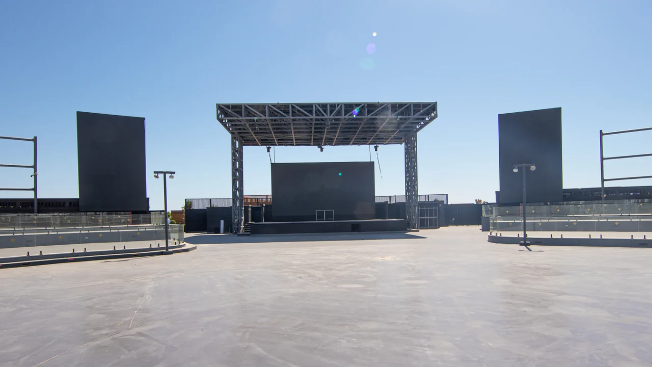 Palco de eventos ao ar livre vazio, com estrutura metálica e refletores apagados