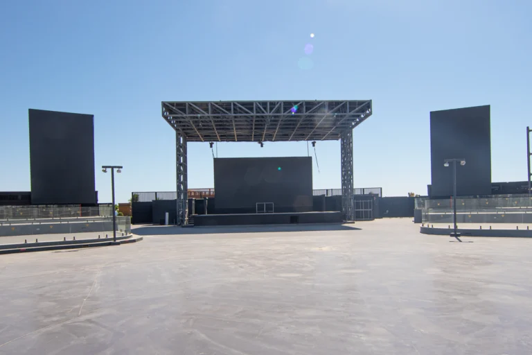 Palco de eventos ao ar livre vazio, com estrutura metálica e refletores apagados