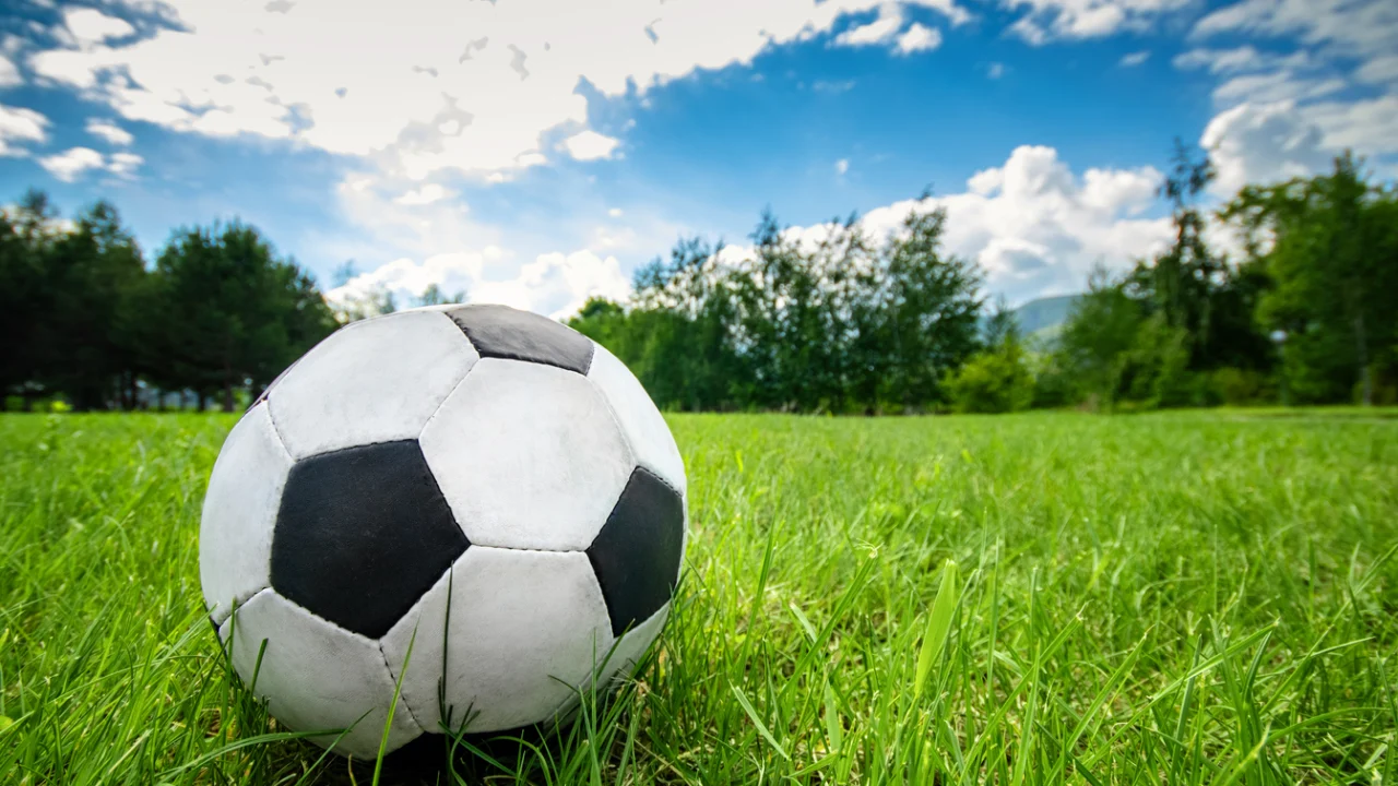 Bola de futebol sobre gramado verde em campo aberto