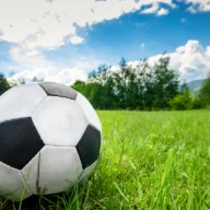 Bola de futebol sobre gramado verde em campo aberto