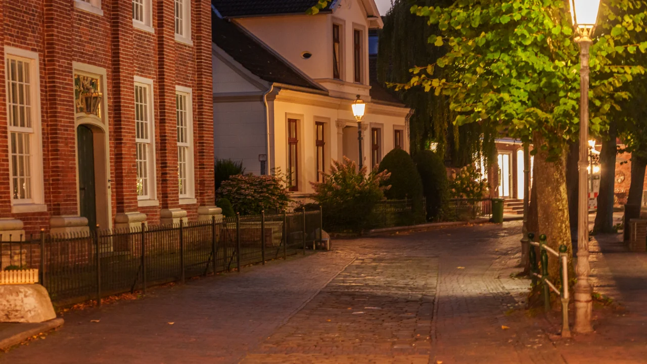 Rua residencial iluminada por poste de luz à noite, sem pessoas