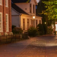 Rua residencial iluminada por poste de luz à noite, sem pessoas