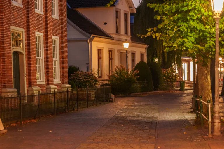 Rua residencial iluminada por poste de luz à noite, sem pessoas
