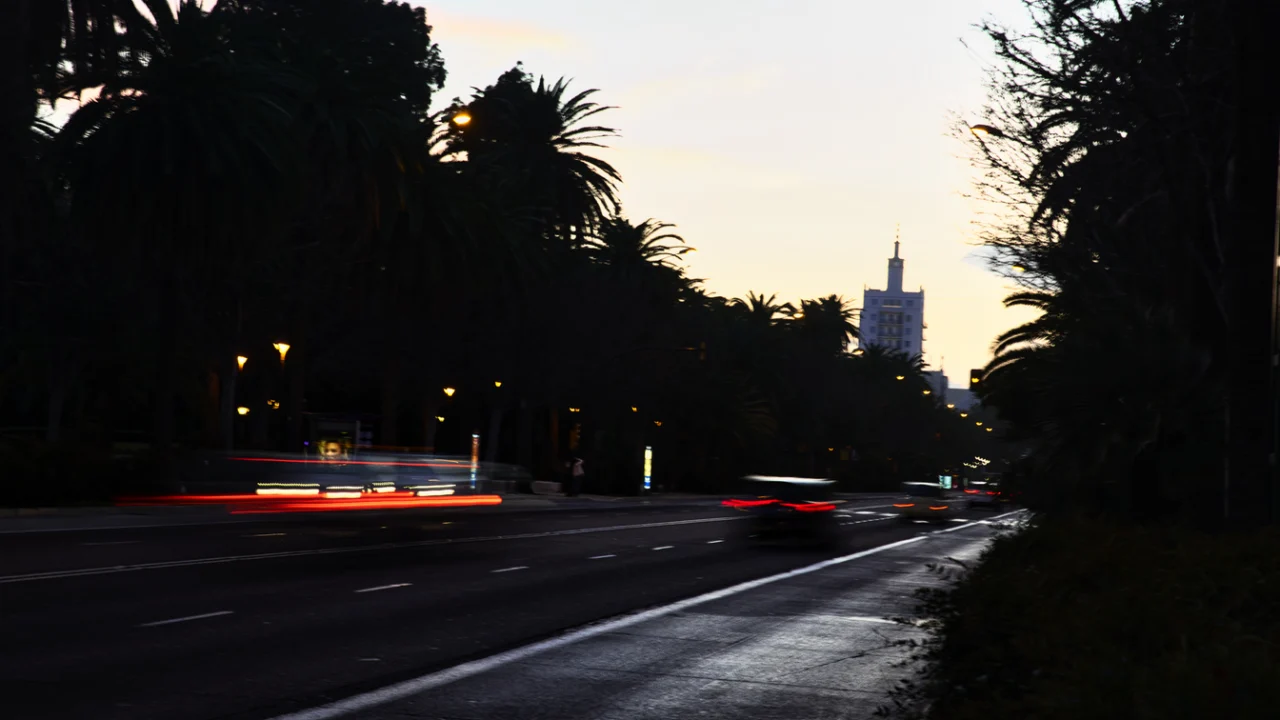 Avenida urbana à noite com rastros de luz de carros em movimento