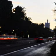 Avenida urbana à noite com rastros de luz de carros em movimento