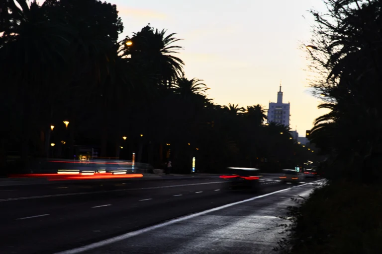 Avenida urbana à noite com rastros de luz de carros em movimento