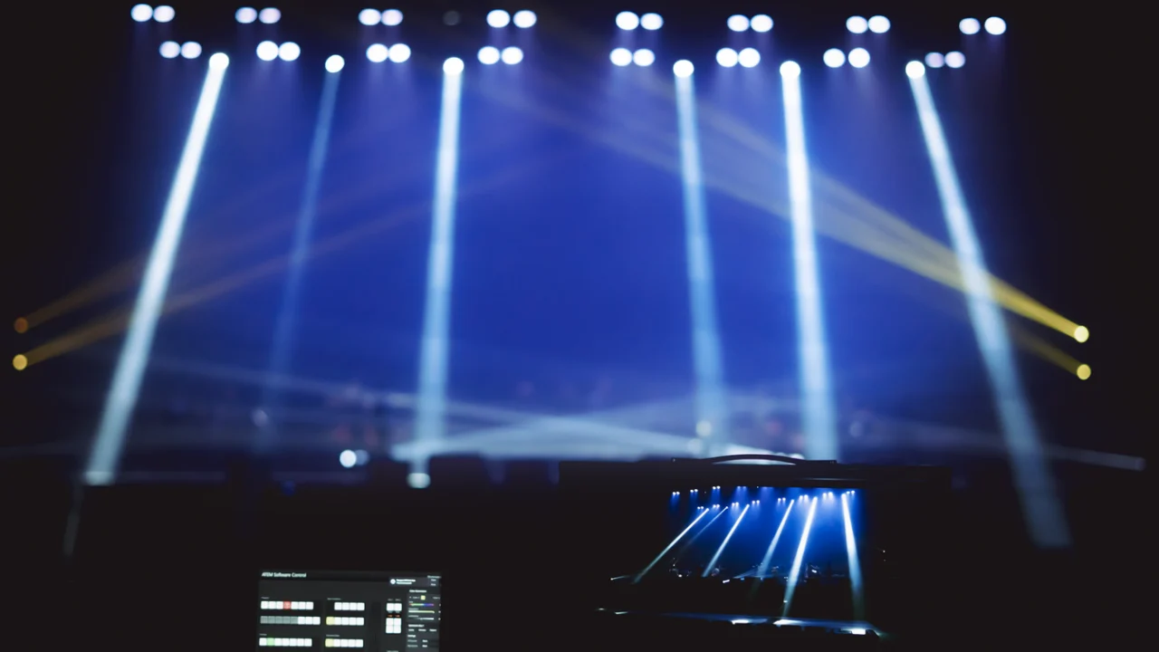 Palco de show com luzes coloridas acesas e plateia vazia no escuro
