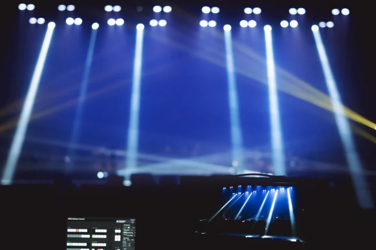 Palco de show com luzes coloridas acesas e plateia vazia no escuro