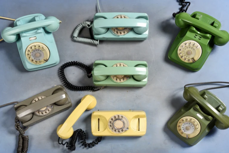 Telefones antigos de disco expostos em vitrine com luz suave.